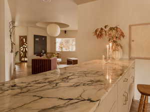 Kitchen featuring light stone counters, dark wood-style flooring, a kitchen bar, and a peninsula