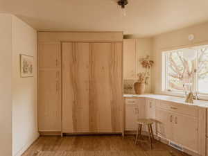 Kitchen with light brown cabinetry, light wood-type flooring, light countertops, and pendant lighting