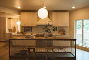 Kitchen with recessed lighting, decorative backsplash, decorative light fixtures, light wood-style floors, and light brown cabinetry