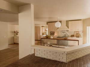 Kitchen with wall chimney exhaust hood, dark wood finished floors, and butcher block countertops