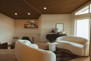 Living area with lofted ceiling, brick wall, wood finished floors, and wooden ceiling