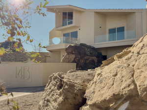 Modern architectural exterior in St George, Utah with light brick, glass balconies, and massive natural rock features built into the design.