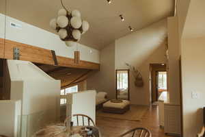 Dining area with wood finished floors and high vaulted ceiling