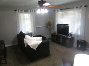 Living area featuring carpet, healthy amount of natural light, and ceiling fan