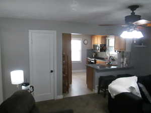 Kitchen featuring decorative backsplash, stainless steel appliances, a peninsula, a ceiling fan, and light brown cabinets
