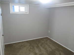 Empty room featuring dark colored carpet and baseboards