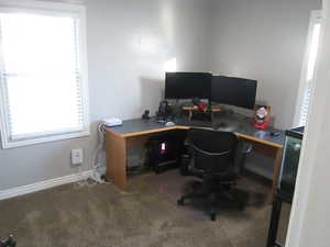 Office space featuring dark colored carpet and baseboards