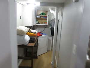 Laundry area featuring washer / clothes dryer, light wood-type flooring, and cabinet space