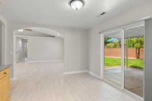 Empty room with light wood-style flooring and arched walkways