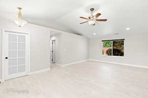 Spare room with light wood-style flooring, vaulted ceiling, a ceiling fan, and recessed lighting