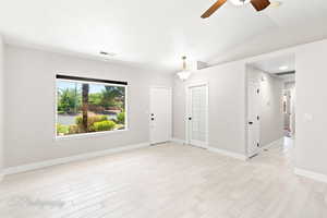 Unfurnished room featuring ceiling fan, light wood-style flooring, and vaulted ceiling