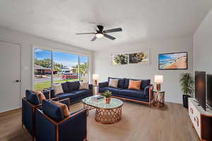 Living area featuring wood finished floors, healthy amount of natural light, and ceiling fan