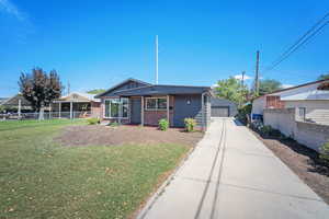 View of front facade with brick siding, a detached garage, and an outbuilding