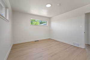 Empty room with light wood-type flooring and a smoke detector