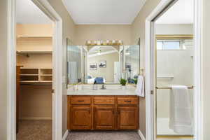 Ensuite bathroom with a shower stall, vanity, a walk in closet, carpet floors, and a textured ceiling