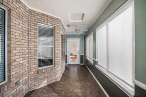 Corridor with brick wall, a textured ceiling, ornamental molding, and dark tile patterned flooring