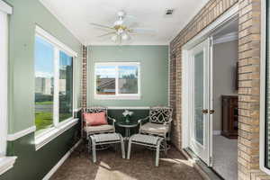 Sunroom / solarium featuring brick wall, crown molding, tile patterned flooring, and a textured ceiling
