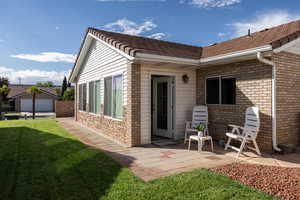 Back of property with a yard, a patio, and brick siding