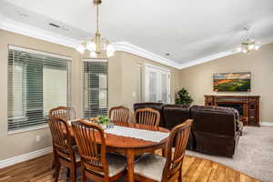 Dining area with crown molding, a fireplace, wood finished floors, lofted ceiling, and a chandelier