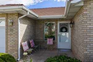 Doorway to property featuring brick siding, a garage, and a patio area