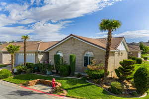 Single story home featuring a garage, brick siding, a front yard, and a tiled roof