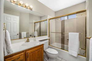 Full bath featuring enclosed tub / shower combo, vanity, and tile patterned flooring