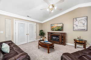 Living area featuring french doors, lofted ceiling, carpet floors, ornamental molding, and a glass covered fireplace