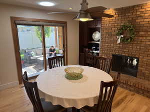 Dining area featuring light wood-style floors, a fireplace, a ceiling fan, and recessed lighting