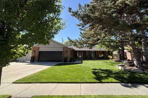 Ranch-style home featuring concrete driveway, a front lawn, a garage, and brick siding