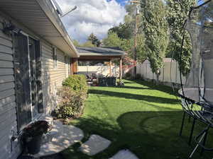 Fenced backyard with a trampoline and a patio