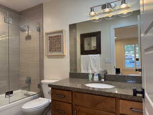 Bathroom with bath / shower combo with glass door and vanity