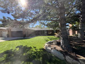 View of property exterior featuring brick siding, a lawn, a garage, and driveway