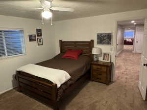 Carpeted bedroom featuring a textured ceiling and ceiling fan