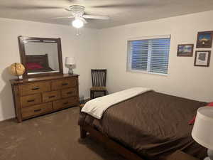 Bedroom with a textured ceiling, colored carpet, and a ceiling fan