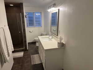 Bathroom with dark tile patterned flooring, a stall shower, and vanity