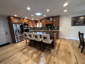 Kitchen featuring tasteful backsplash, recessed lighting, a breakfast bar area, stainless steel appliances, and a center island