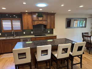 Kitchen with light wood-style flooring, brown cabinetry, a center island, and recessed lighting