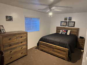 Carpeted bedroom featuring ceiling fan and a textured ceiling