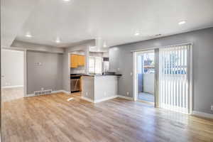 Kitchen with dark countertops, a peninsula, recessed lighting, light wood finished floors, and dishwasher
