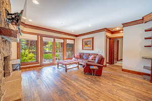 Living room with light wood finished floors, crown molding, recessed lighting, and french doors