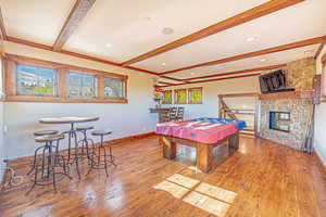 Recreation room with beamed ceiling, light wood-style flooring, billiards, and a fireplace