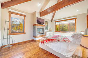 Bedroom featuring beam ceiling, light wood finished floors, a fireplace, high vaulted ceiling, and recessed lighting
