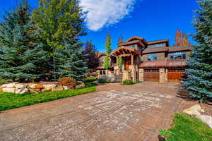 View of front facade featuring stone siding, driveway, and a garage