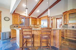 Kitchen with backsplash, light stone counters, a kitchen bar, built in refrigerator, and recessed lighting