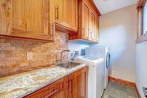 Washroom with washing machine and clothes dryer, cabinet space, and light stone finish floors