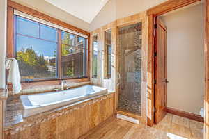 Bathroom with a stall shower, a bath, and lofted ceiling