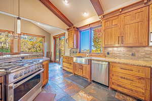 Kitchen with appliances with stainless steel finishes, light stone counters, backsplash, pendant lighting, and a chandelier