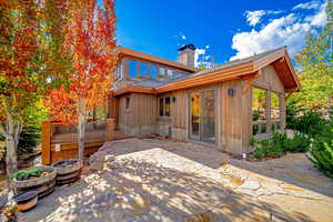 Back of property with a chimney, a patio, a shingled roof, and a deck