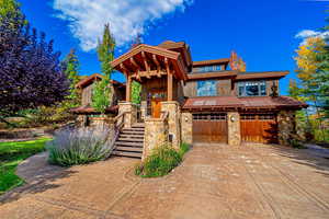 View of front of home featuring a garage, stone siding, concrete driveway, and stairs