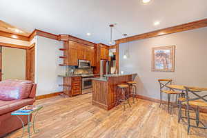 Kitchen featuring brown cabinetry, dark stone counters, a peninsula, decorative backsplash, and recessed lighting
